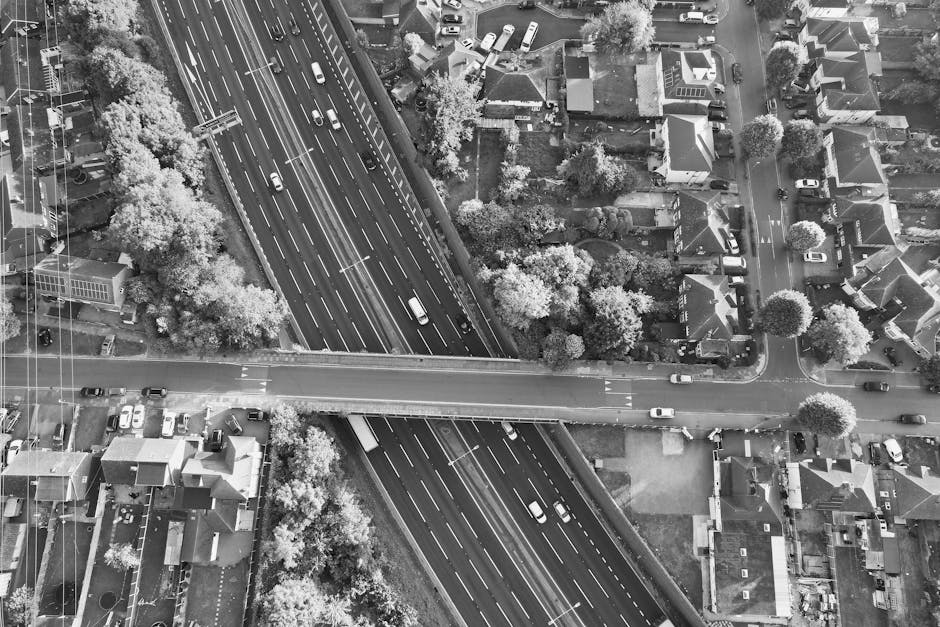 Aerial view of a busy freeway intersection in a residential area, captured in black and white.